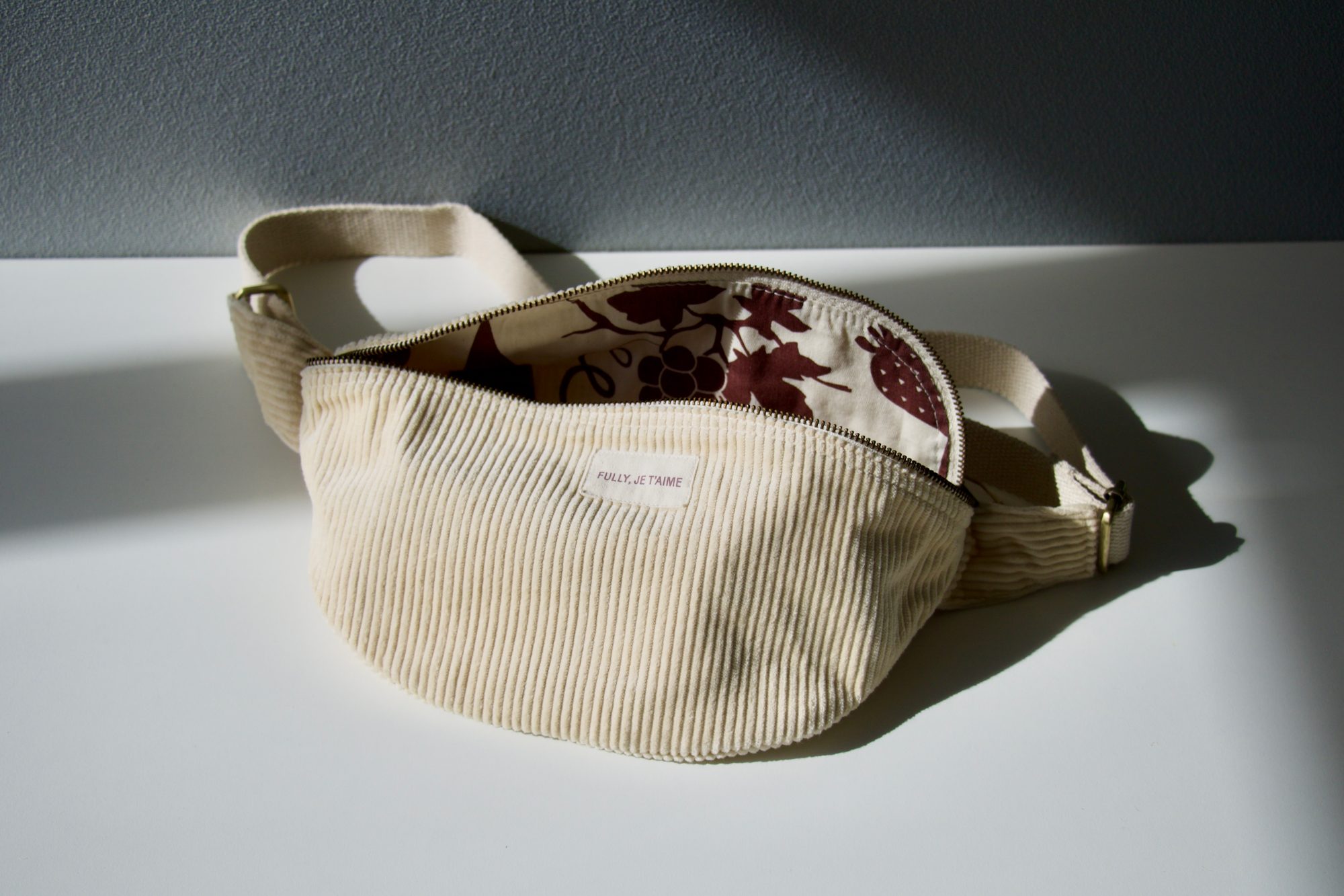 banane-velours-cotele-fully-je-t-aime Sac banane personnalisé en velours côtelé écru avec étiquette « Fully, je t'aime » Office du Tourisme de Fully