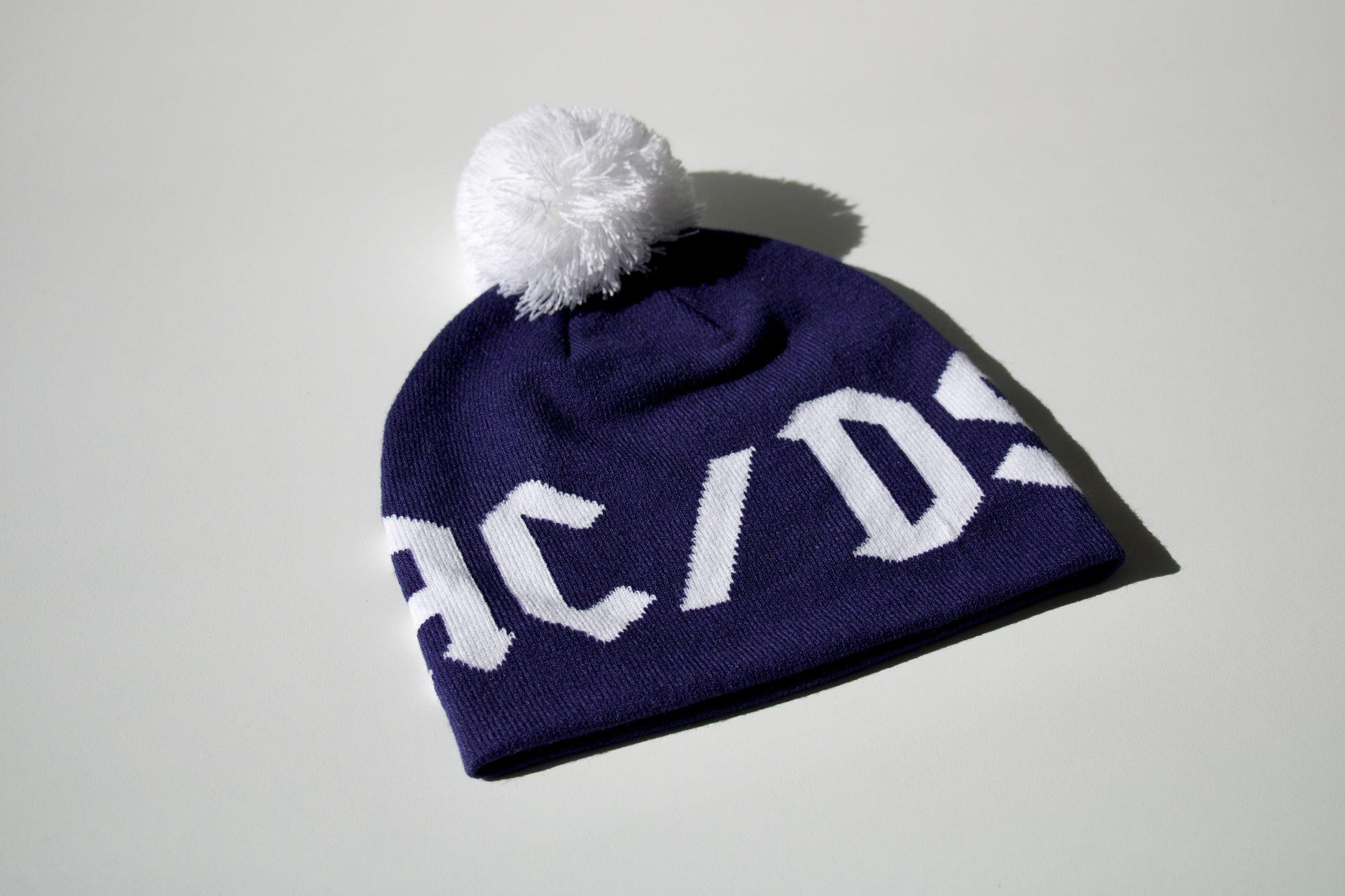 bonnet-pompon-jacquard-personnalise Bonnet à pompon bleu marine avec inscription tricotée en jacquard