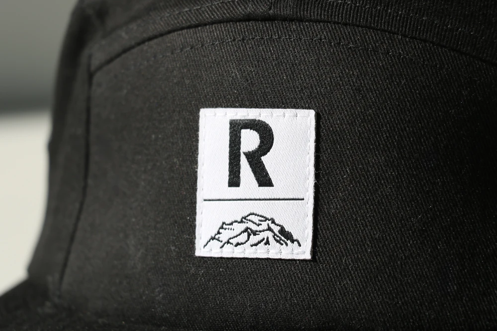 casquette-5-panel-noire-raiffeisen-detail Casquette 5 panels noire personnalisée Raiffeisen avec étiquette tissée