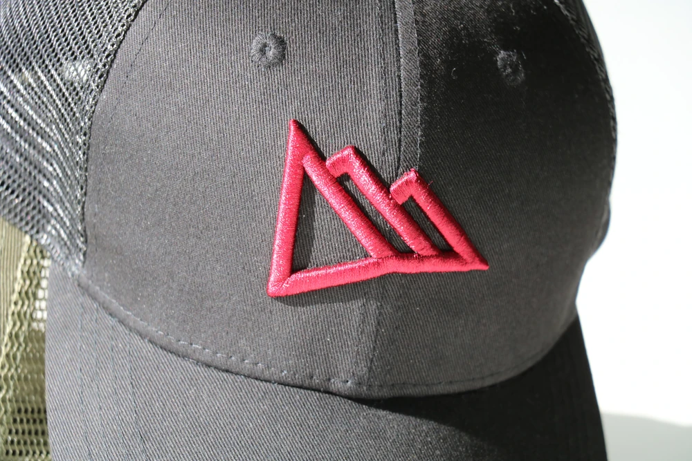 Gros plan sur la broderie 3D du logo Région Dents du Midi sur une casquette