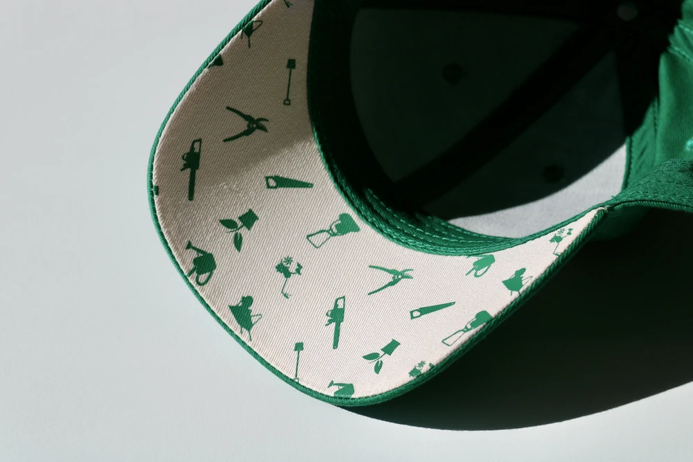 casquette-trucker-verte-sous-visiere-imprimee Sous-visière imprimée personnalisée d'une casquette trucker verte, motif outils de jardin