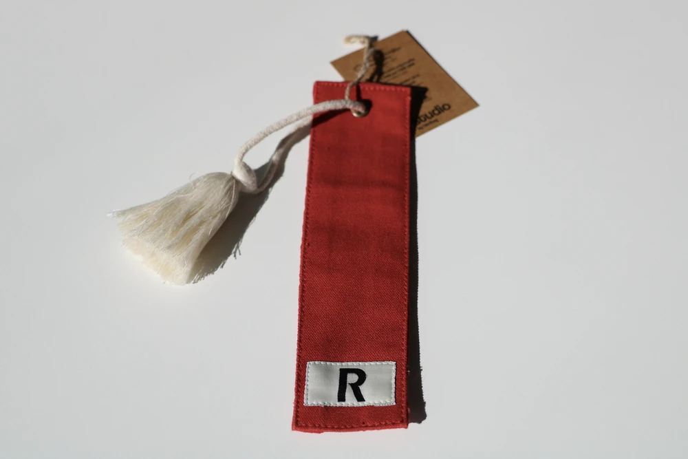 marque-page-tissu-personnalise-raiffeisen Marque-page en tissu rouge personnalisé avec étiquette R et pompon